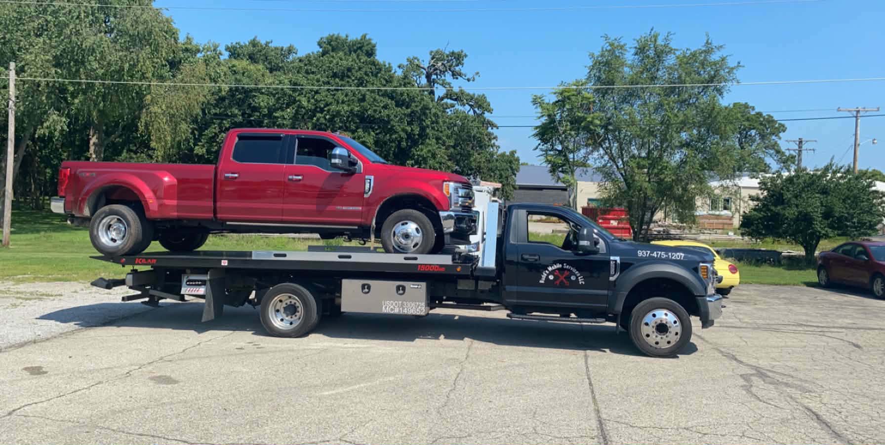 Rudd's flatbed tow truck hauling a red pickup truck